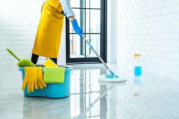 Person in blue rubber gloves using mop for wiping floor