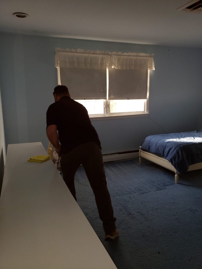 A person cleaning a bedroom with blue carpets