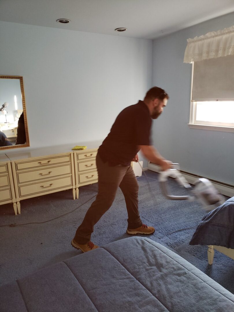 A man vacuuming a room with a window