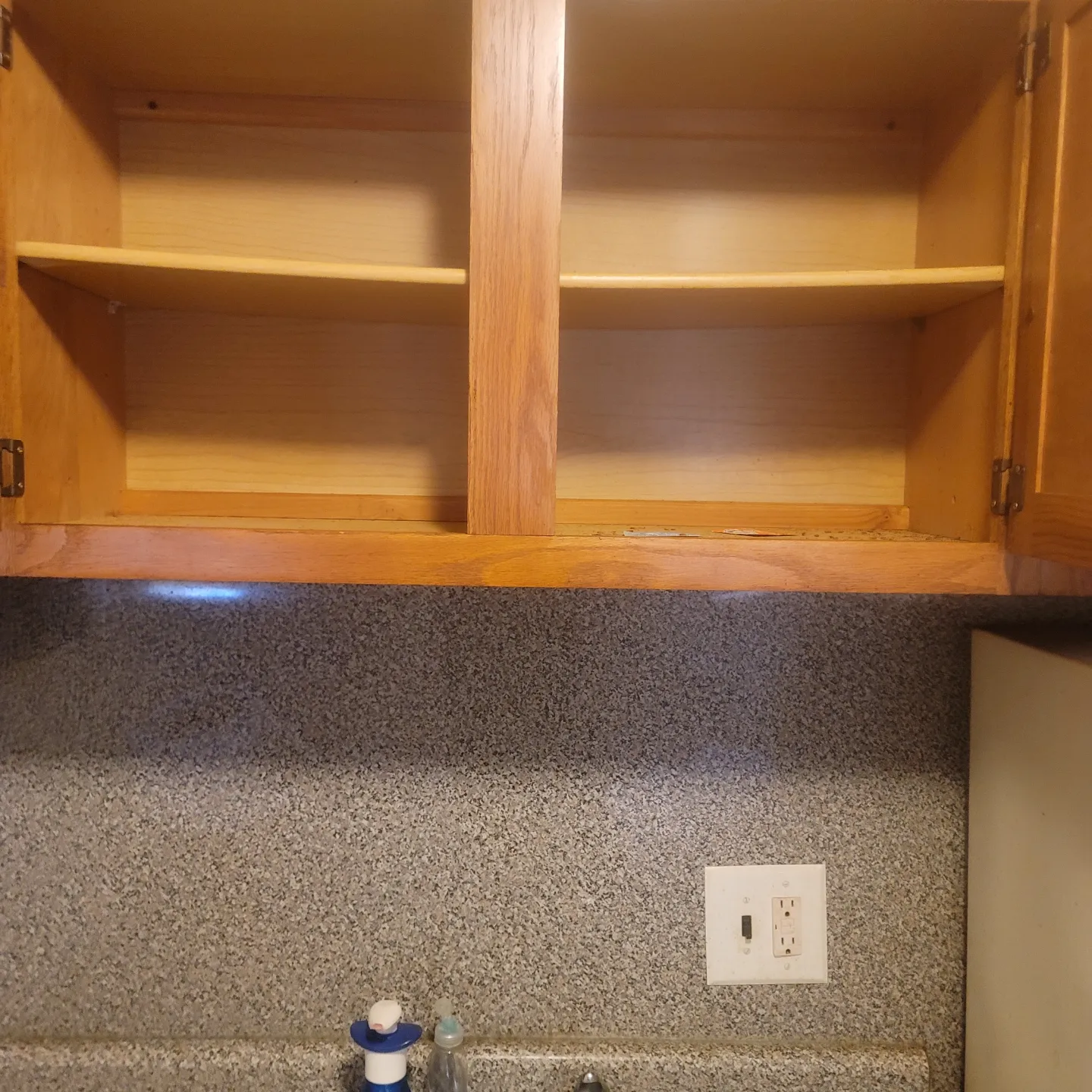 An empty cabinet in a kitchen with a power socket